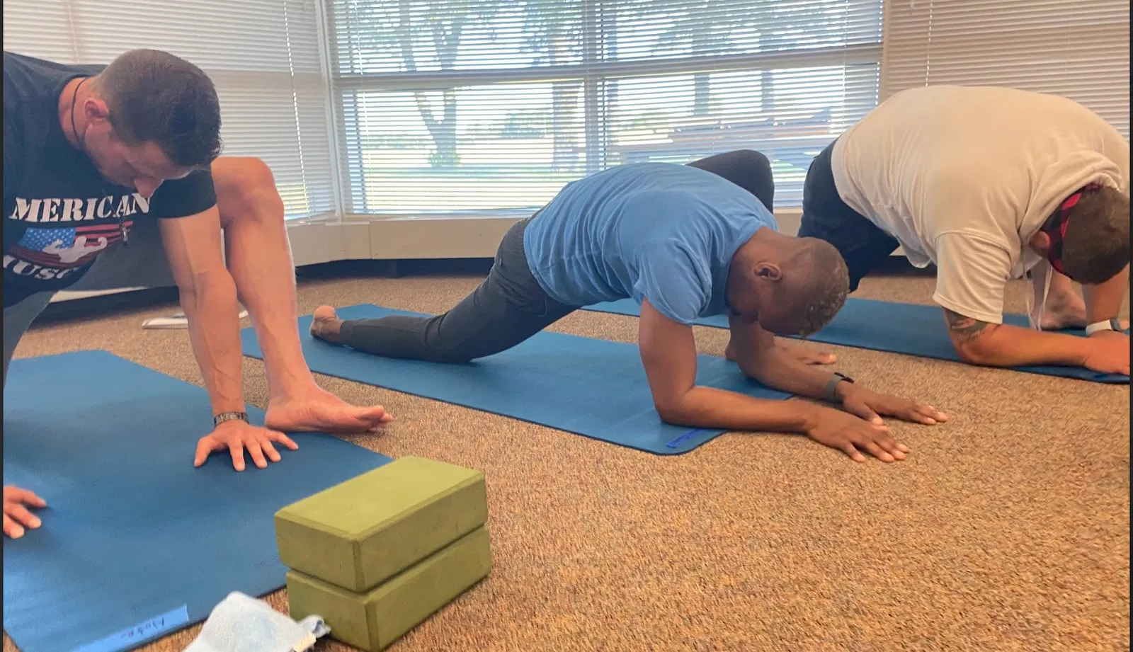 3 men on yoga mats practicing Pigeon Pose