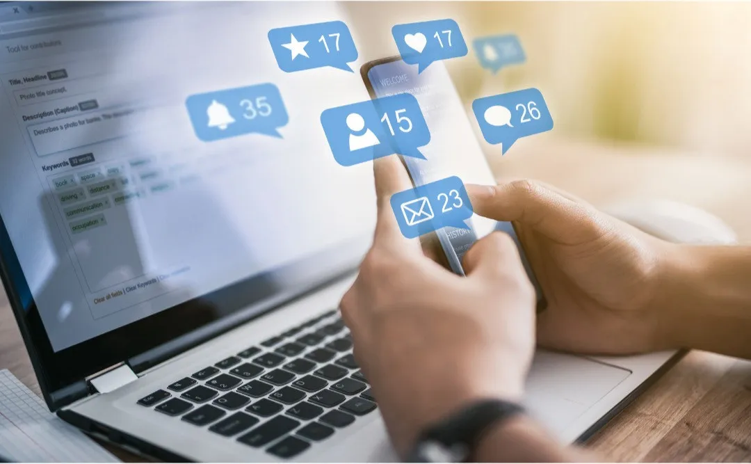 Person checking social media on phone while working on computer.
