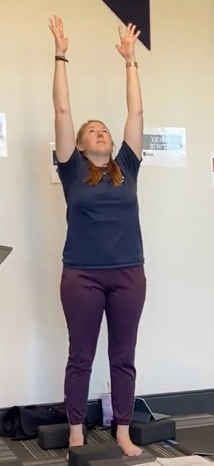 Woman holding arms up over head in a yoga pose.